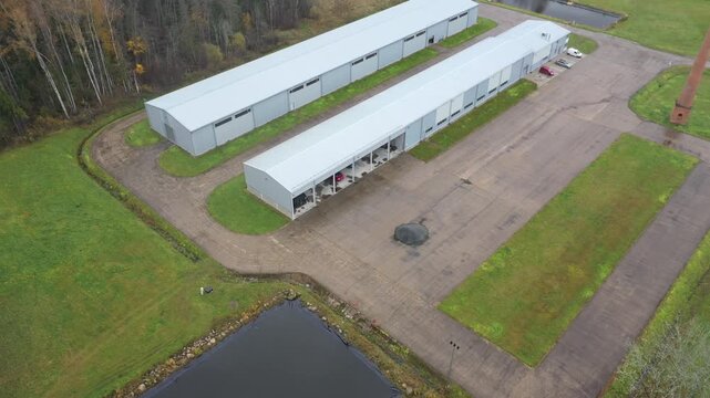 Valka, Latvia - October 29, 2025: Aerial view of industrial storage facility with surrounding greenery, camera pans right revealing scene depth