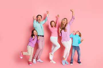 Fototapeta premium Family celebration of love and togetherness as parents and children cheer jump and pose against a pink background in a bright joyful day of fun and holiday spirit
