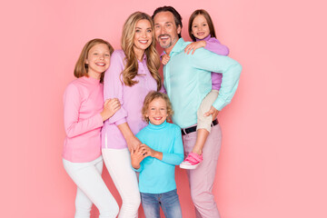 Family portrait with parents and children celebrating together in pastel outfits against a pink background