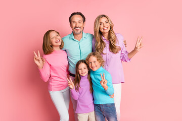 Obraz premium Happy family portrait with parents and three kids smiling together against a pink background for warmth and togetherness