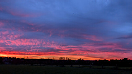 Fiery sunrise over the landscape with colorful clouds. 
