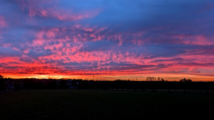 Fiery sunrise over the landscape with colorful clouds. 