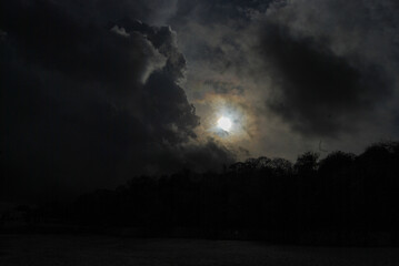 Sunlight breaks through dark clouds above the silhouette of trees.
Sunlight filters through thick dark clouds, creating a striking contrast with the silhouette of the trees below. 