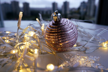 A string of Christmas lights shaped like snowflakes and a single silver-pink Christmas ball with a...
