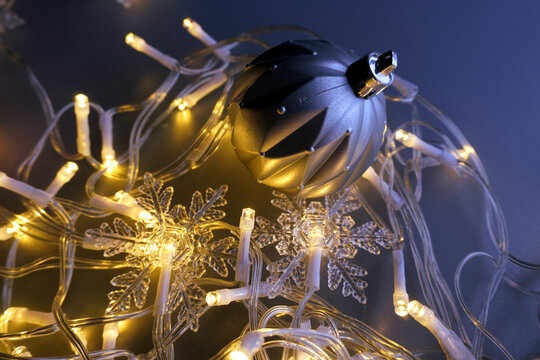 Christmas time. A single silver pink ornament with a unique, faceted design is the focal point of the image. Christmas light-snowflakes