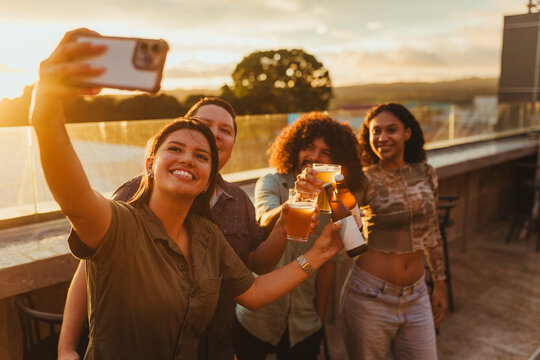 Happy friends making a toast and taking a selfie at sunset