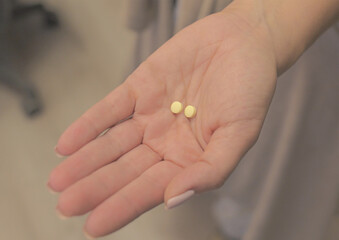woman holds two yellow tablets for health