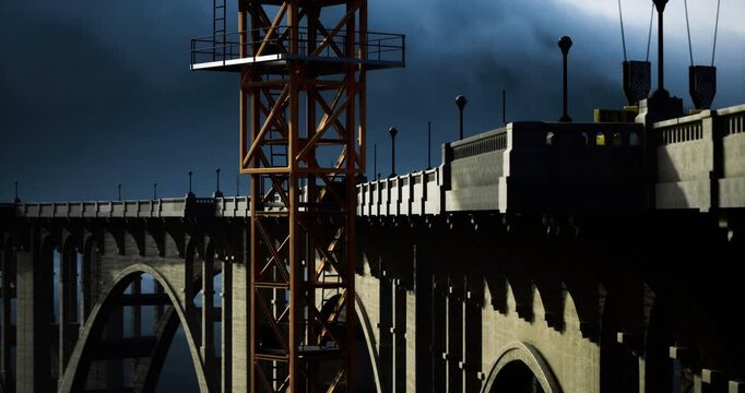 Cranes elevate materials against a dramatic twilight sky as workers diligently build a majestic bridge. The scene captures the energy and ambition of engineering marvels in progress.