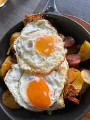 two fried eggs with fried potatoes in cast iron pan