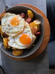 two fried eggs with fried potatoes in cast iron pan