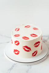Beautiful birthday white cake decorated with red lips traces texture Happy Valentine's cake on the white marble background