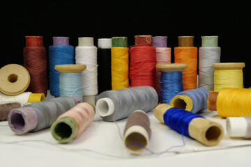 Spools with multi-colored threads on black background, close-up shot