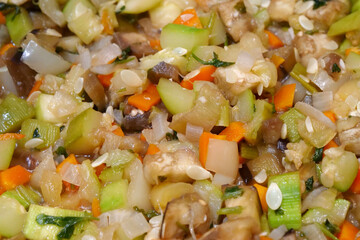 Vegetable stew is cooked on gas stove in metal pan. Vegetable ragout
