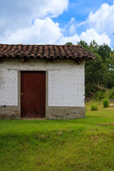 Rustic white house with wooden door in rural area under blue sky with clouds