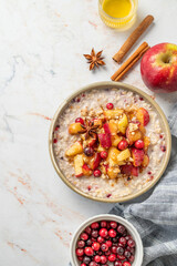 Flat lay of overnight oatmeal with apple, honey, cranberry and cinnamon in a plate on a marble background