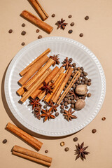 Various spices on a plate against a bright beige background with shadows.