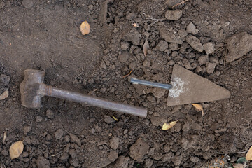 Metal trowel and hammer on soil, top view