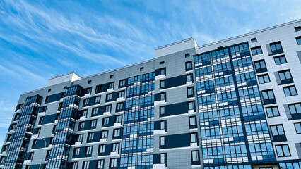Close-up of the facade of a modern residential building featuring blue and gray panels and large...