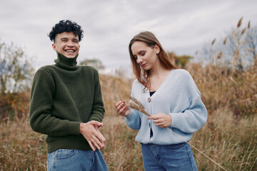 Authentic moment between friends outdoors in a field, candid smiles, natural posture, and genuine...