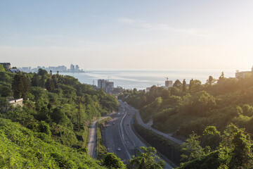 Scenic view of winding road passing above tunnel in Batumi, Georgia, surrounded by lush green hills...
