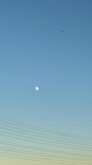 Minimalist Crescent Moon and Distant Plane Silhouetted Against an Evening Ombre Sky.