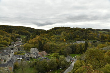 Fototapeta premium Le village de Sosoye entouré de collines boisées en automne sous un ciel gris à Anhée (Dinant)