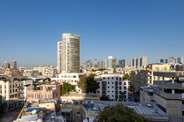 Tel Aviv, Israel, Elevated view of a dense urban landscape with diverse architecture, combining towers and older apartment buildings. In the background stands the tall round Moshe Aviv Tower