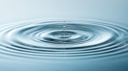 Water droplet impacting surface creating concentric ripples in blue liquid.