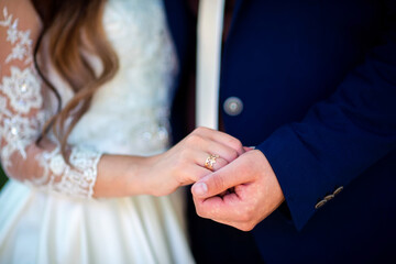 Obraz premium Bride and groom holding hands close-up. Close-up of bride and groom holding hands showing wedding ring during ceremony