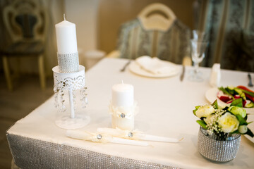 Wedding candles and elegant table decoration. Elegant wedding table with white candles, silver holders and floral decoration creating romantic atmosphere