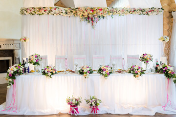 Luxury wedding banquet table with flowers and decorations. Bright wedding banquet table decorated with flowers, candles and elegant white fabric creating luxury atmosphere