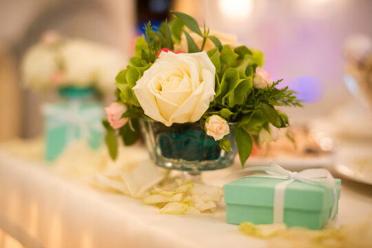 Wedding table decoration with roses and gift box. Beautiful wedding table with white roses in vase and turquoise gift boxes as elegant decor