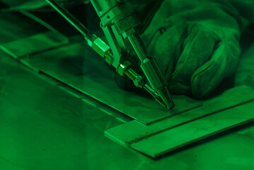 Close up of a human hand performing laser welding on metal, bright flying sparks. Robotization and automation of the weld process. Robot welding steel. Industrial welding and working with metal parts