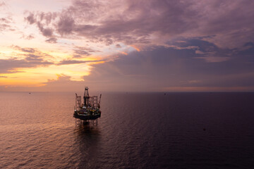 Aerial view of offshore jack up rig and offshore platform during sunset for oil and gas exploration and production.