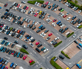 High angle drone view showing many colorful cars filling a large outdoor carpark.