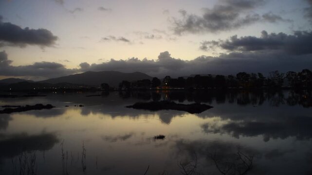 A predawn pan clip of a wetland wildlife habitat with beautiful light and cloud reflections on the still water.