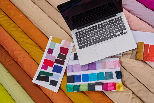Fabric rolls and laptop, color swatches, design concept, textiles and technology, creative workspace, fashion designer inspiration, material selection, online collaboration, product photo studio shot. - Powered by Adobe