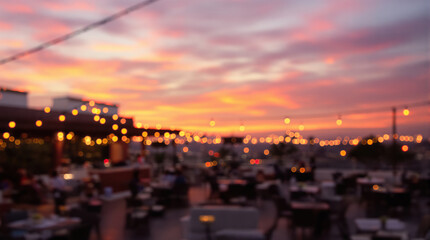Rooftop bar with blurred bokeh lights and a vibrant sunset sky, creating a beautiful and atmospheric evening scene