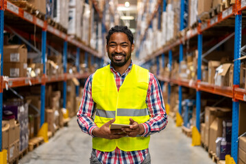 Warehouse worker smiling while holding a tablet in a large distribution center