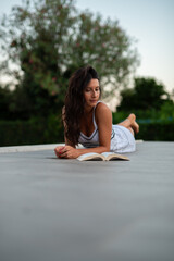 Fototapeta premium girl in white dress read book on poolside
