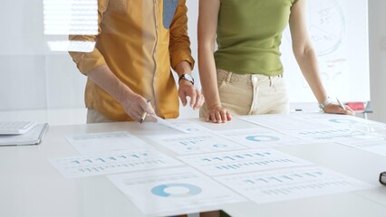 Business professionals analyzing financial reports, pointing at charts during collaborative meeting, discussing data with focused professional demeanor