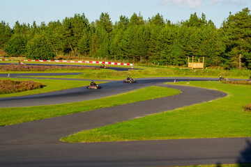 Go-Kart Racers on Curving Outdoor Track – Motorsport Action in Green Landscape