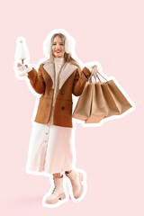 Beautiful young woman in winter clothes with shopping bags and toy Christmas tree on pink background