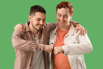 Male friends bumping fists on green background