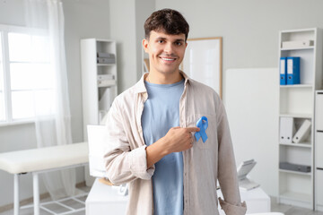 Young man with blue ribbon in clinic. Prostate cancer awareness concept