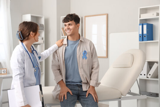 Young man with blue ribbon and female doctor in clinic. Prostate cancer awareness concept - Powered by Adobe