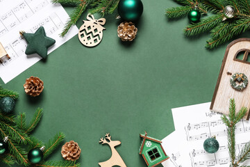 Frame made of music sheets, fir branches and Christmas decorations on green background