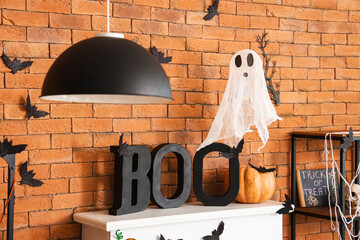 Word BOO with ghost and Halloween pumpkin on fireplace in living room