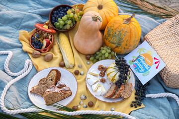 Pumpkins, delicious food and greeting card with text HAPPY THANKSGIVING on beach