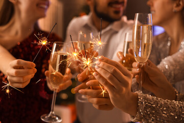Young people with champagne and Christmas sparklers at party, closeup